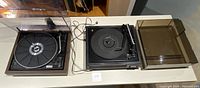 Wide view showing both vintage turntables on table; Kenwood KC-850 on left with wood finish, Realistic 44 on right with black base and clear cover.