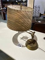 Front angled view of lamp showing fabric shade, brass base and adjustable arm.