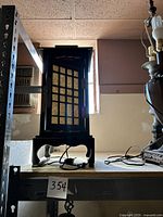 Side view of vintage Japanese lantern style table lamp showing wood frame and paper panels, placed on a shelf.