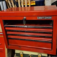 Front view of red Craftsman tool chest with four drawers and lock with keys attached.
