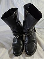 Front view of Harley Davidson women's black leather boots with studded ankle straps, showing condition and zipper closure.