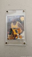Front of Kobe Bryant NBA Hoops rookie card showing player action image, name, Lakers logo and card details in protective case.