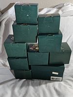 Stack of 10 green boxes containing Harmony Kingdom figures, showing general lot contents and condition.