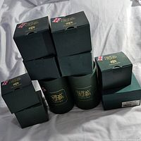 Stack of 8 green Harmony Kingdom boxes, some cylindrical, others square, all closed and branded.