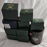Stack of green Harmony Kingdom Treasure Jest boxes with one black cylindrical box, showing all 8 boxed figurines.