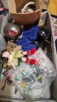 Box containing various collectible items including sports helmets and a blue felt letter 'M'