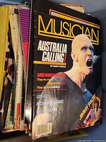 Stack of various vintage magazines showing front covers including a Musician magazine featuring a bald man and text about Australian and musical content.