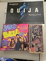Top view of Ouija Mystifying Oracle, Saved By The Bell and Science Cube board games showing box covers and titles