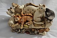Front view of the figurine showing multiple cats on a tufted couch with patterned cushions in various poses.