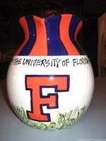 Front view of the ceramic pitcher showing large orange and blue 'F' and text 'THE UNIVERSITY OF FLORIDA' around the neck with blue and orange stripes.