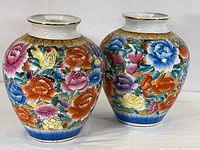 Photo of two matching hand painted floral vases with gold trim, showing front and side views.