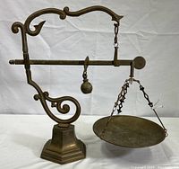 Full view of brass balance scale showing frame, beam, counterweight and pan