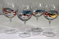 Group of four Cornet Barcelona wine glasses with colorful swirls and gold overlays on a white background.