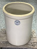 Front and side view of large stoneware pot showing light beige glaze and blue Garden City Pottery Co. mark with capacity '12'.