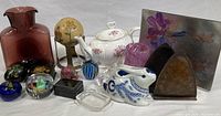 Photo showing entire lot of decorative items including glass vase, hand painted egg, teapot, bookends, coin bank, boxes, paperweights, and more.