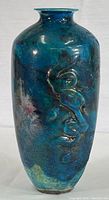 Full view of the tall rounded vase showing blue glaze with smoky black highlights and embossed abstract design.