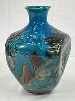 Front and side view showing blue glaze with dark smoky black embellishments and the flared neck of the vase
