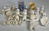 Wide shot showing entire collection of Pillsbury Dough Boy items including shakers, cookie cutters, plastic cup, figurines, and plush doll.