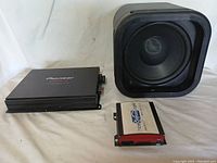 Three audio items: black Pioneer amplifier, silver and red Pro digital audio player, and black Roku speaker with dent