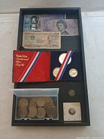 Entire lot viewed from above showing banknotes, US Silver Proof Set, boxed coins, individual coins and mounting holder