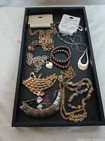 Full view of assortment jewelry items in black display tray against light background