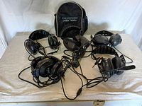 All five aviation communication headsets arranged on a table alongside a Lightspeed branded carrying case.
