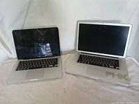 Two Apple MacBooks, one MacBook Pro and one MacBook, displayed side by side showing keyboards and screens.