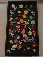 Tray with assorted new Crocs charms showing characters, logos, flowers, and shapes.