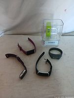 Six fitness watches shown on a plain surface including five loose watches and one iFitness watch in packaging.