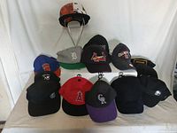 Front view of 14 assorted hats on a metal hat rack showing various sports and branded caps including baseball teams and casual styles