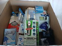 Photo of a box containing new bathroom items including a Wahl Lithium Multigroom grooming kit, cotton swabs, disposable cotton pads, black soap dispensers, and other personal care items in original packaging.