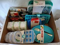 Top down image of the box contents showing multiple food storage containers, ice cube trays, salad bowl with utensils, and other items.
