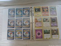 Open binder pages showing Pokémon trading cards on right and card backs on left, displayed in clear page holders.