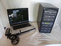 Toshiba laptop and PRO DVD duplicator tower shown side by side on white surface.