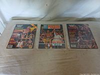 Three WWF wrestling magazines laid out on a cloth surface, showing covers including Hulk Hogan images