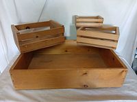 Photo showing the four wooden wine crates, three small and one large, empty and displayed together.