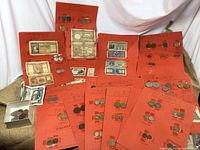 Overview of multiple red card sheets with taped coins and banknotes, plus a small box of loose coins