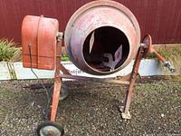 Front view of mixer showing orange drum, frame and wheels
