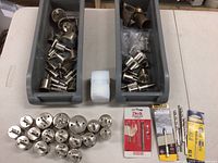 Diamond hole saws arranged in rows by size, with two gray plastic trays holding additional hole saws and some drill bits in packaging on table.