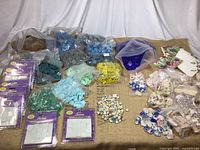 Wide view of assortment of glass and ceramic mosaic tiles displayed on burlap