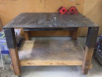 Front view of work table showing steel top, wooden shelf, steel legs and two magnetic welding squares on top