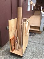 Full view of plywood rolling rack loaded with plywood board, cork roll, dowels, cabinet door and metal trim