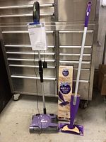 Shark lightweight vacuum and Swiffer Wet Jet Wood mop side by side with Swiffer box visible.