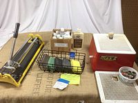 Overall view of manual tile cutter, glass grinder, sanding sponges, patinas box, cement bottle and grinding bits.