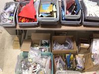 Wide view of multiple plastic bins and cardboard boxes filled with assorted stained glass scrap pieces of various colors