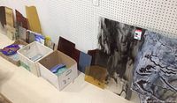 Assorted glass sheets laid out on table against pegboard