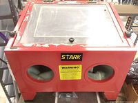 Front and top view of red sandblasting cabinet showing hinged lid with viewing glass and two glove ports