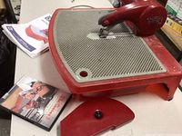 Front view of red Taurus 3 ring saw on table with instruction manual and DVD