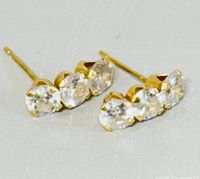 Close-up photo showing the front and setting of 14K yellow gold earrings with three clear round stones.