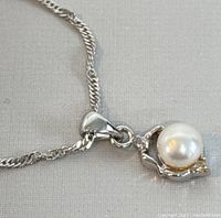 Close-up of the pearl pendant with 18K white gold plating on a delicate chain.